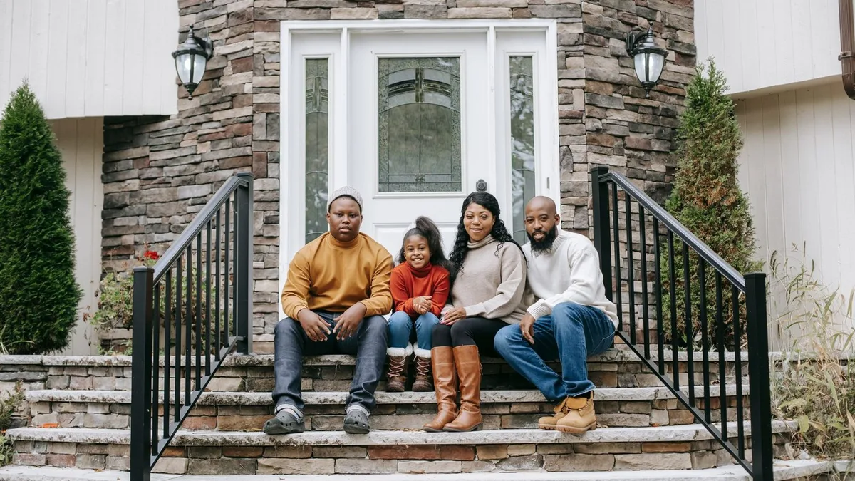 A family sitting together on the front steps of their new Las Vegas home